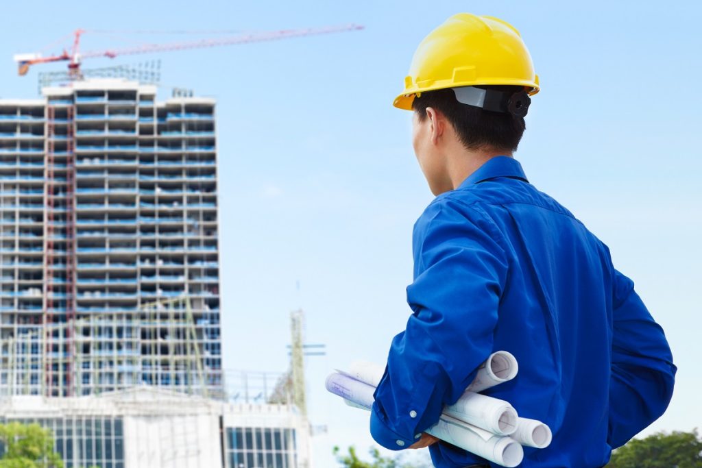 male engineer holding blueprints in a construction site